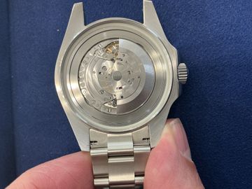 Open watch movement inspected above a repair estimate form