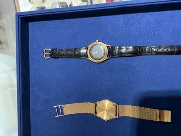 Two vintage gold wristwatches arranged in a workshop tray