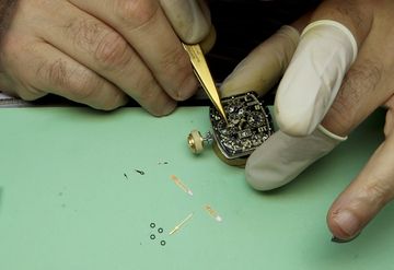 Watchmaker using tweezers on a tonneau-shaped mechanical movement