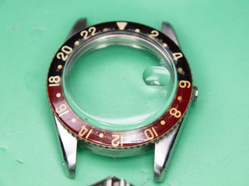 Scratched acrylic watch crystal on a vintage GMT-style case