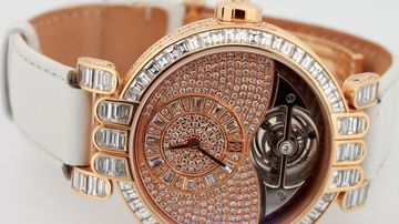 Diamond-set tourbillon watch held in a white glove