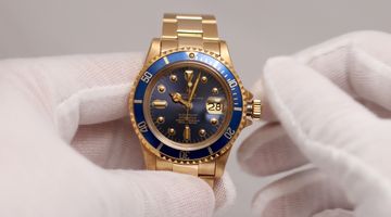 Vintage gold dive watch held in gloves for condition assessment