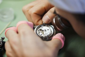 Watch movement being inspected by a technician wearing finger cots