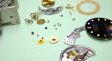 Rolex Submariner movement, dial, hands, and case components arranged during service