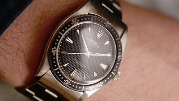 Worn Rolex watch held for close condition inspection