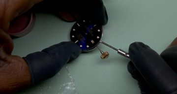Blue-dial Rolex watch being examined with hand tools at a repair bench