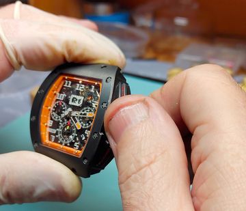 Gloved hands gently operating the crown of a mechanical watch