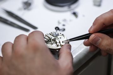 Watch movement being inspected with tweezers