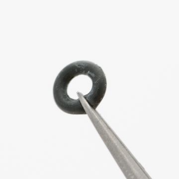 Small black watch gasket held with tweezers
